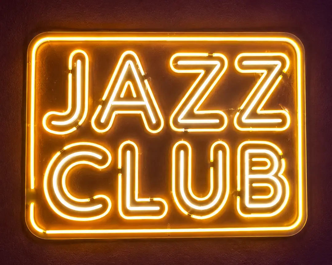 The gold JAZZ CLUB neon sign glowing on a dark wall
