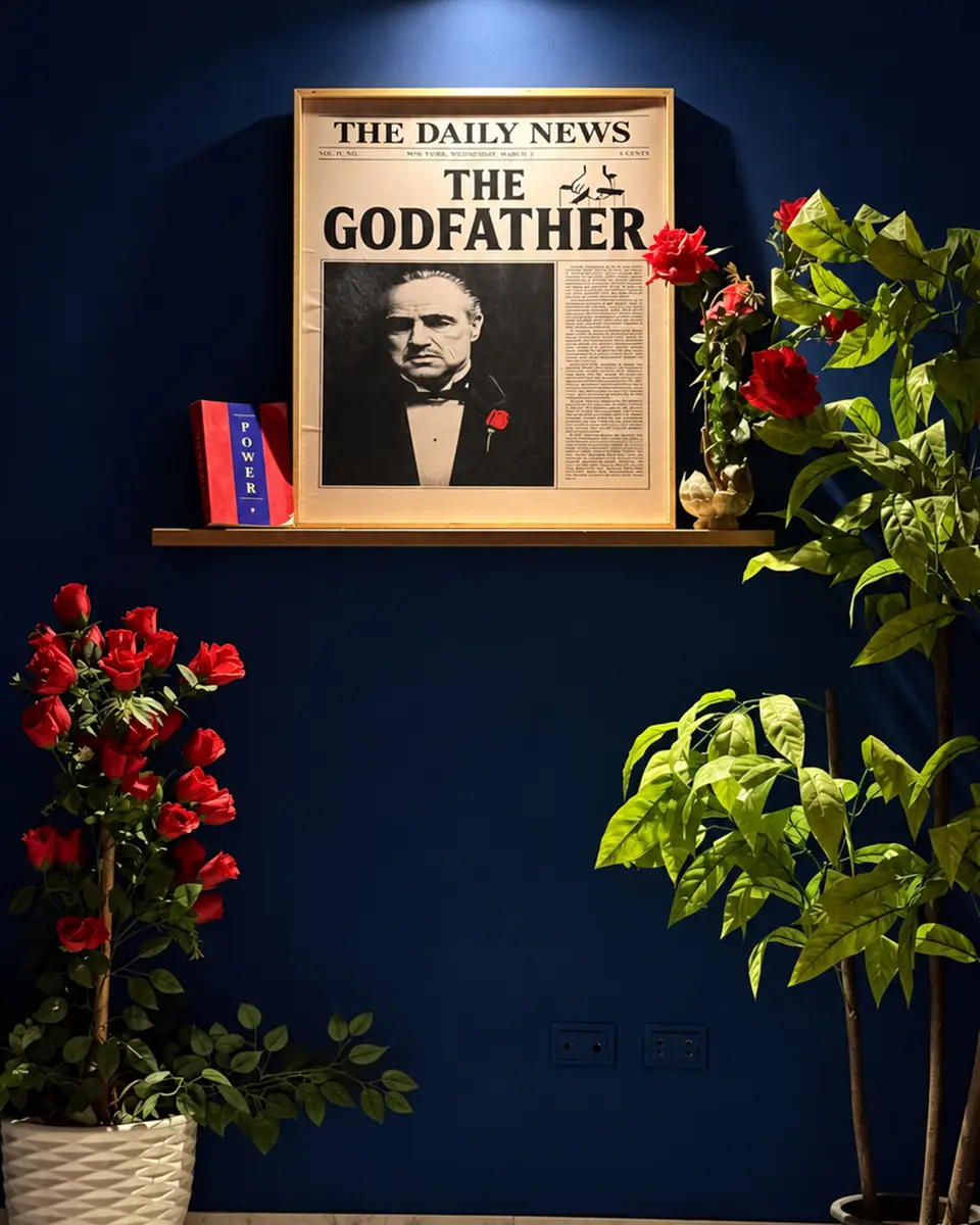 A framed Godfather newspaper print between plants and red roses