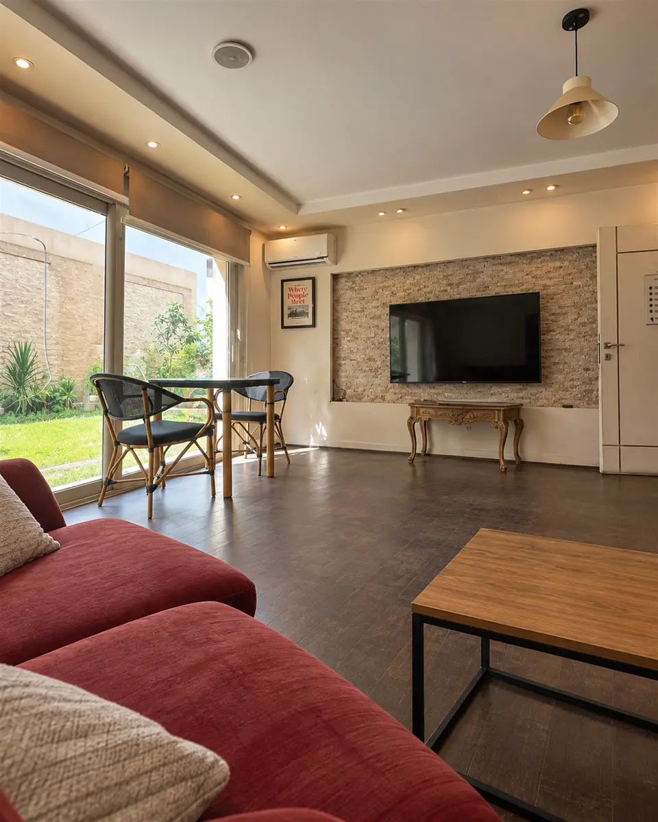 Room 02: red sofas, a stone TV wall and glass doors onto the garden