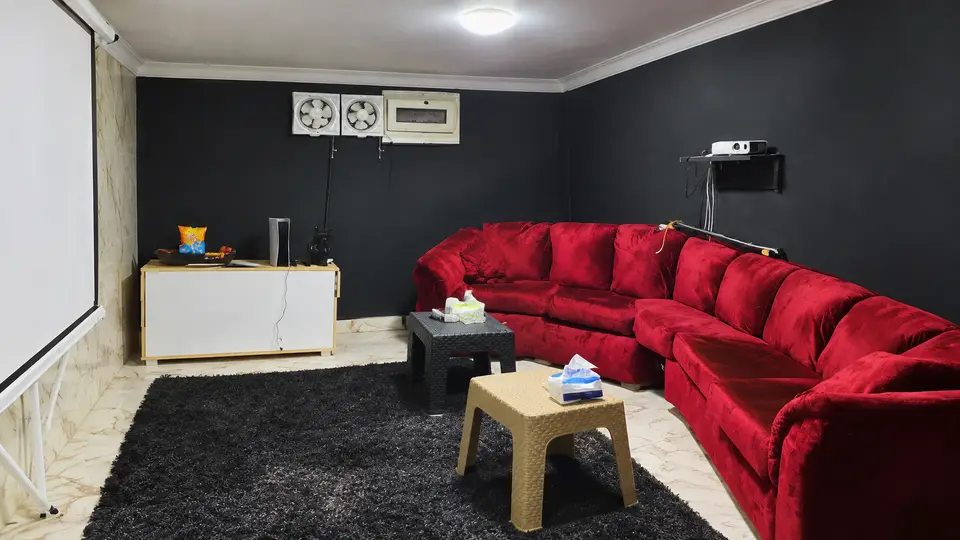 Room 05: a red velvet corner sofa facing a projector screen