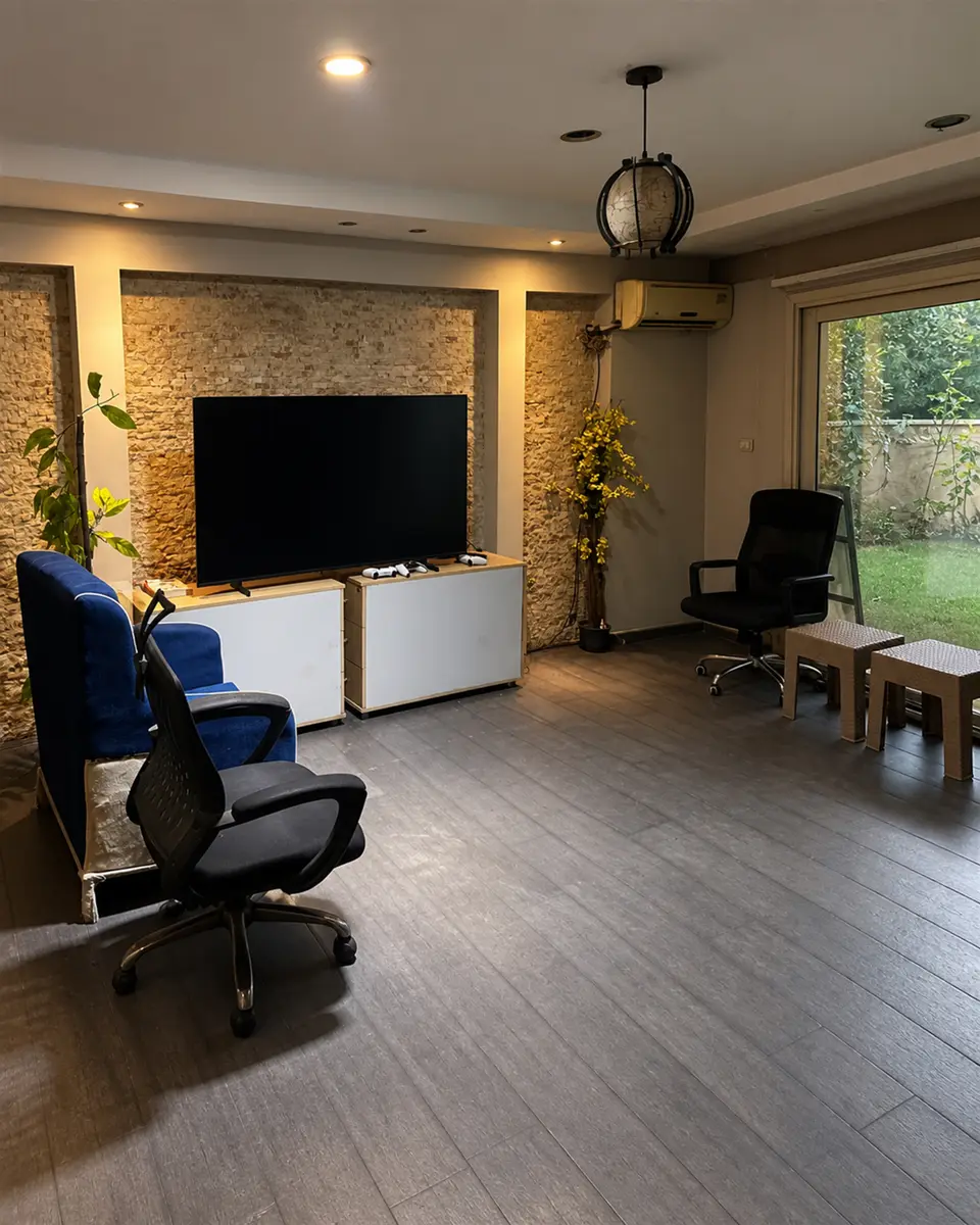 Room 06 from the corner: stone TV wall, gaming chairs and the garden window